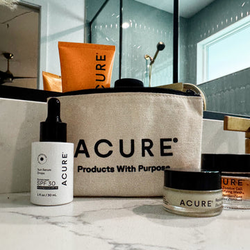 Acure skincare products on a bathroom counter with a beige bag displaying the brand name.